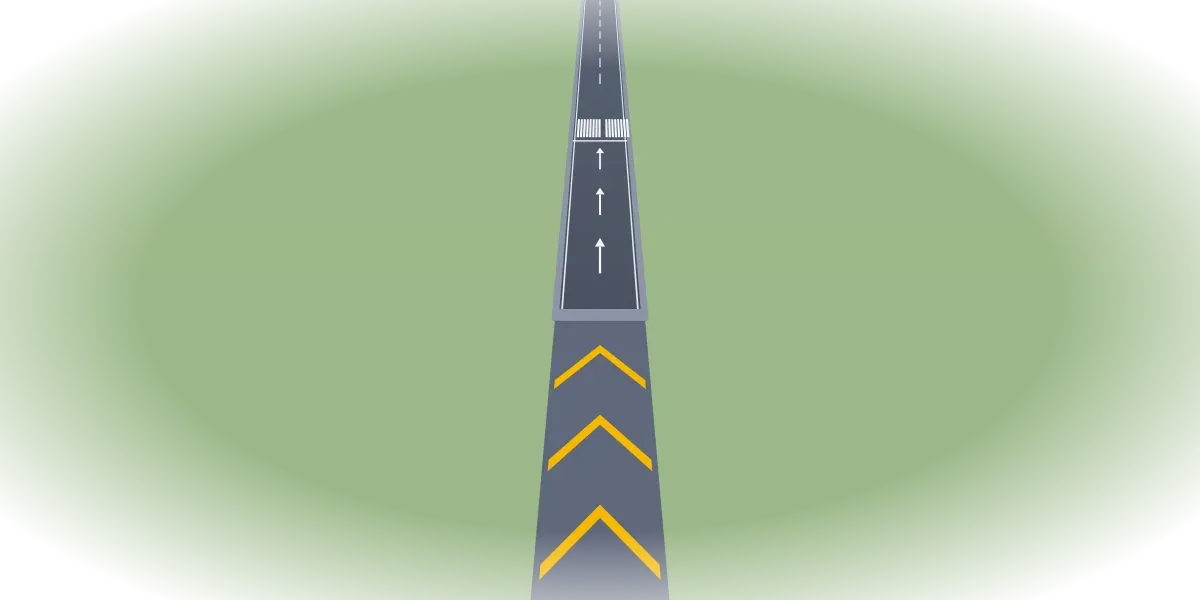 A runway seen from its end, with yellow chevrons on the pavement before it and three white arrows leading to a threshold bar